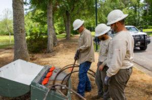 Linemen working outside on side of road.