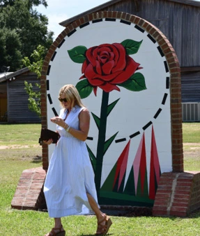 A ribbon-cutting attendee walks in front of Mark Shertzer’s rose mural.