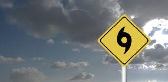 A yellow warning sign featuring a tornado symbol, indicating potential severe weather conditions.